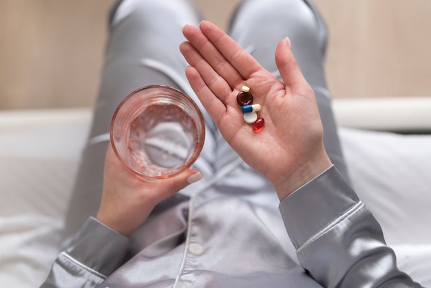 Close up hands holding water glass and pills
