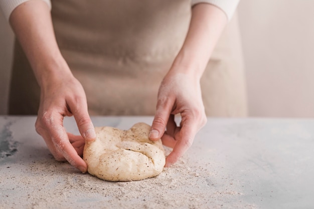 Close-up hands kneading bread dough