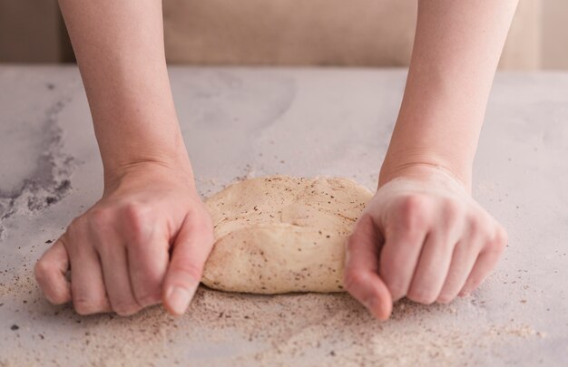 Close-up hands kneading dough