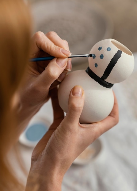 Close-up hands painting pottery item