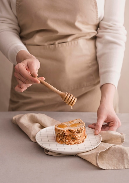 Бесплатное фото Руки крупным планом наливают мед на хлеб