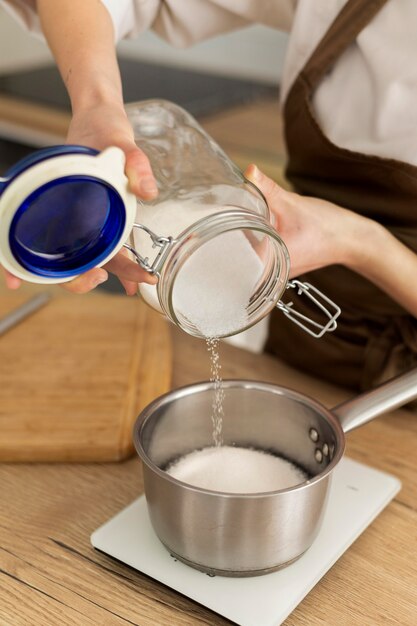 Close up hands pouring sugar in pot