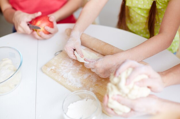 Close-up of hands preparing dough basis for pizzas