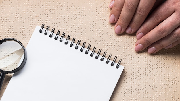 Mani del primo piano che leggono il libro di braille