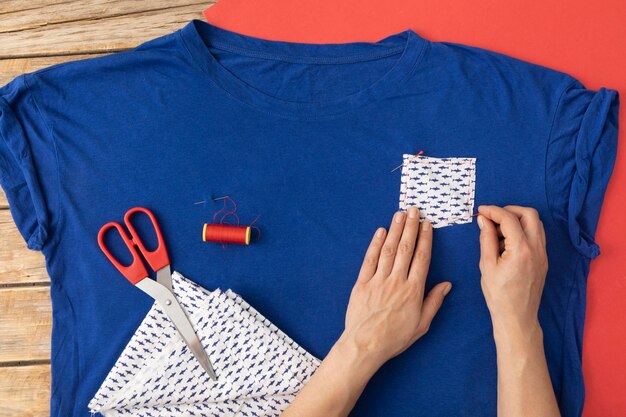 Close-up hands sewing fabric on shirt