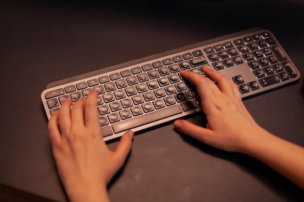 Close up hands shot of gamer pushing the keyboard buttons while playing online shooter video game vi... Free Photo