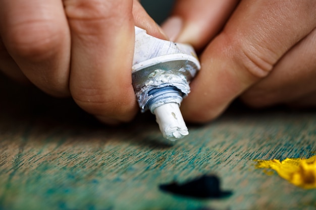 Foto gratuita chiuda in su delle mani che schiacciano la pittura ad olio bianca sulla gamma di colori