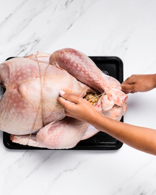 Close-up hands tying up stuffed turkey