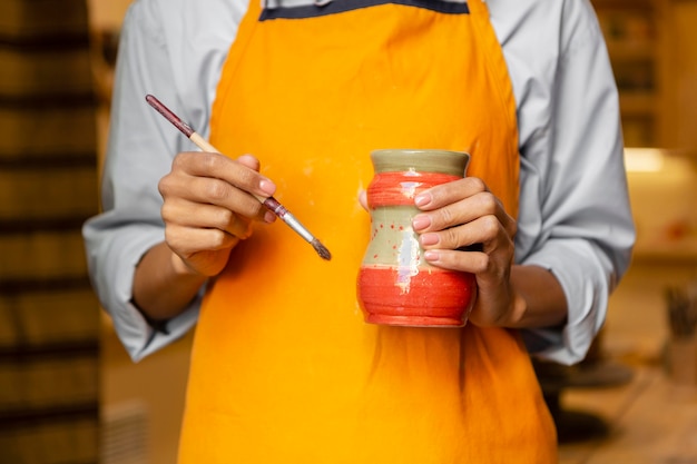 Free photo close up hands with brush and clay pot