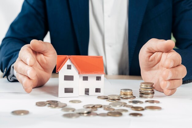 Close-up hands with coins and house