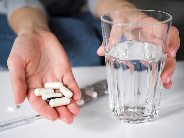 Close-up hands with pills and glass