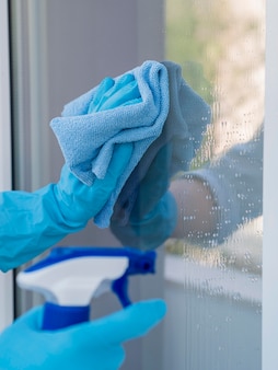 Макро руки в резиновых перчатках моют окна