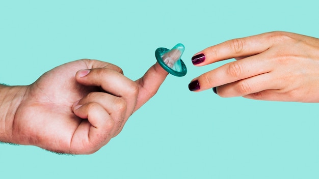 Free photo close-up hands with unwrapped green condom