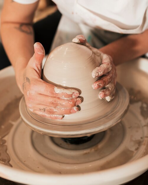陶器のホイールに取り組んでいる手のクローズアップ
