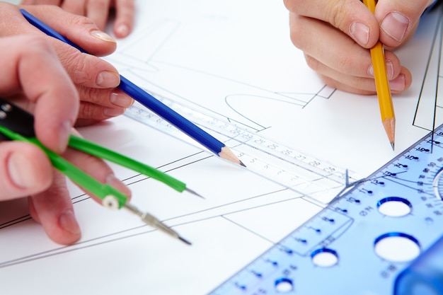 Close-up of hands working with pencils and rulers