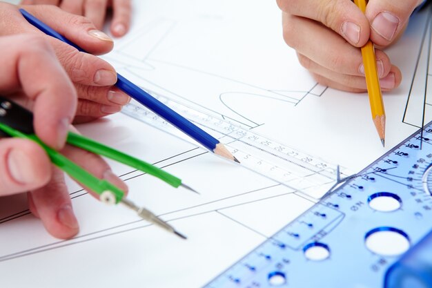 Close-up of hands working with pencils and rulers