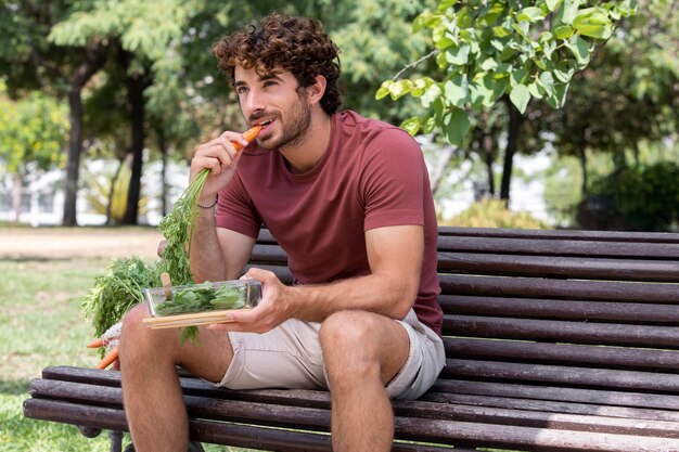 Крупным планом на красивый мужчина ест в парке