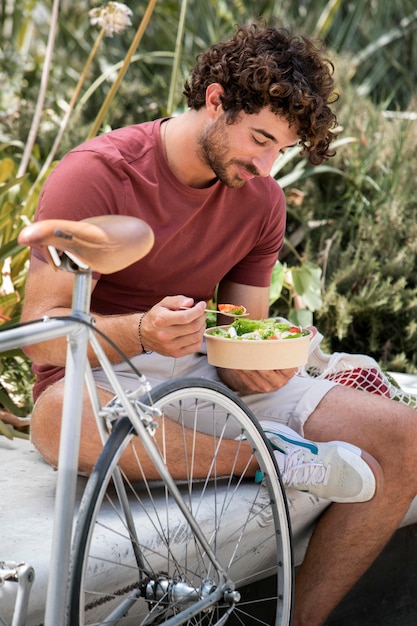 Foto gratuita primo piano su un bell'uomo che mangia nel parco