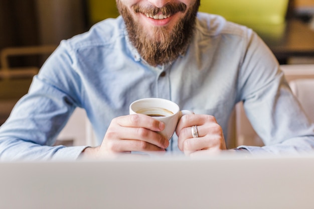 Close-up of a happy bearded man drinking coffee