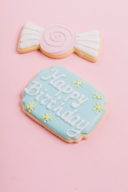 Close-up of happy birthday text on cookie over pink background