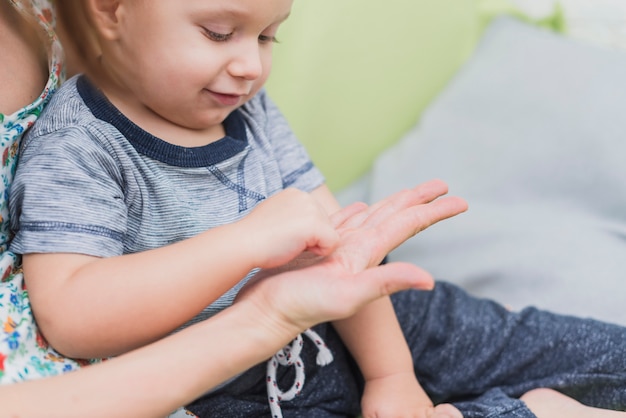 Close-up of happy child playing with his mother's hand