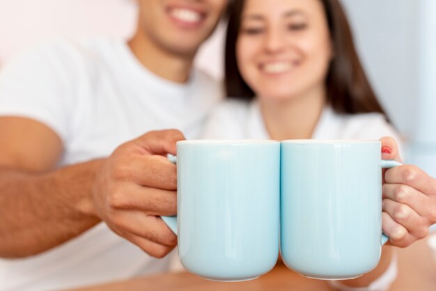 Close-up happy couple holding blue mugs