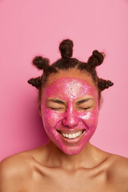 Free photo close up on happy ethnic woman enjoys applying face mask isolated