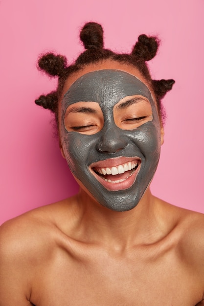 Крупным планом на счастливой этнической женщине нравится применять изолированную маску для лица