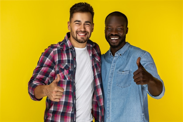 Close up happy European and black guys showing thumbs