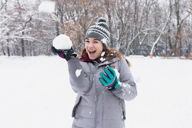 Крупным планом счастливая девушка играет со снегом в лесу