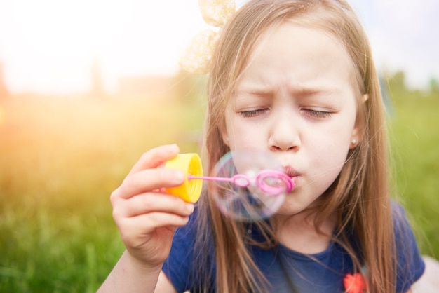 Крупным планом счастливый ребенок играет с мыльными пузырями