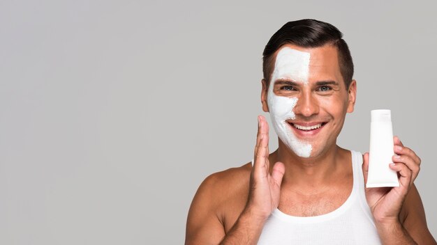 Close-up happy man holding face product