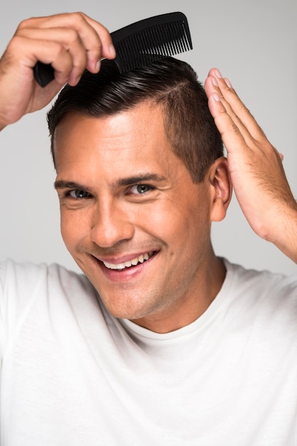 Close-up happy man using hair comb