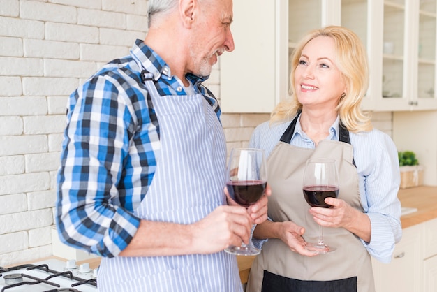 와인을 즐기는 앞치마를 입고 행복 한 노인 커플의 근접 촬영
