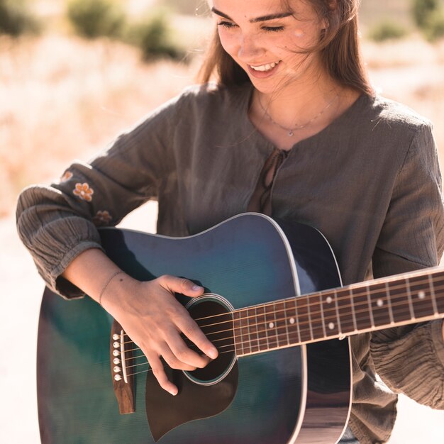 Close-up of a happy teenage girl playing guitar