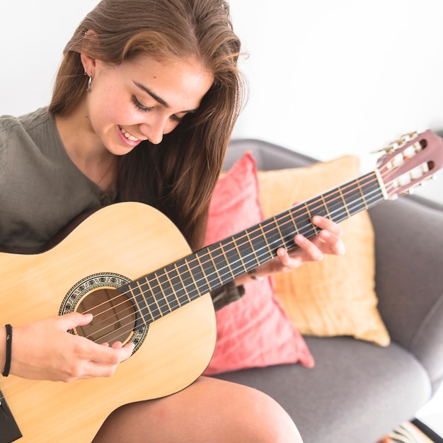 Close-up of a happy teenage girl playing guitar
