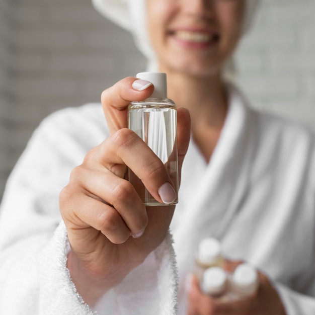 Close-up happy woman holding small bottle