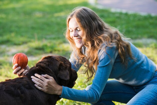 庭で彼女の犬をパッティングする幸せな女性のクローズアップ