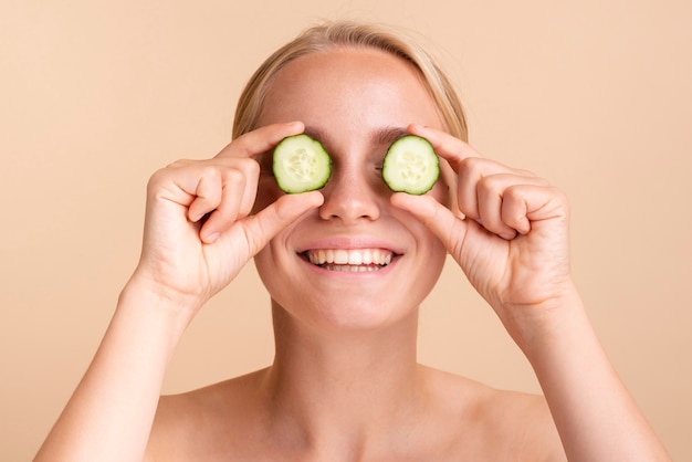 Free photo close-up happy woman with cucumber slices