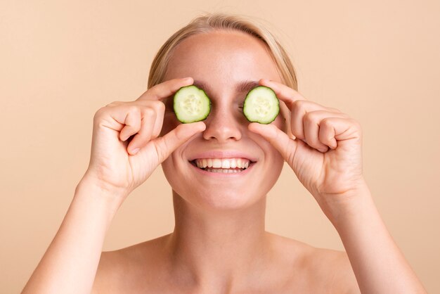 Close-up happy woman with cucumber slices