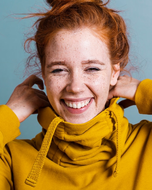 Close-up happy woman with yellow hoodie and grey background