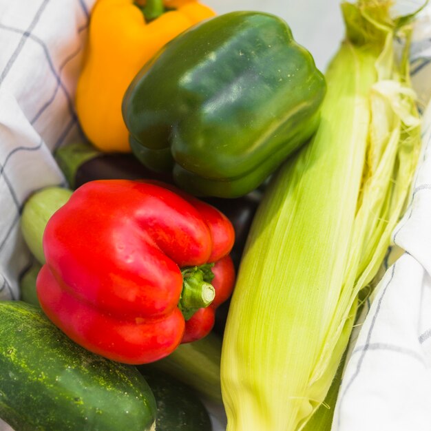 Close-up of harvested bell peppers; corn and cucumber