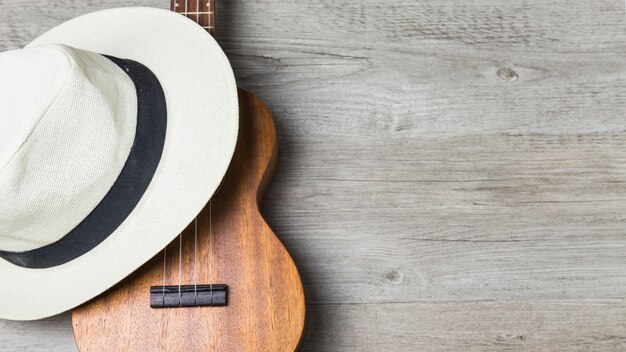 Close-up of hat over the guitar against wooden background