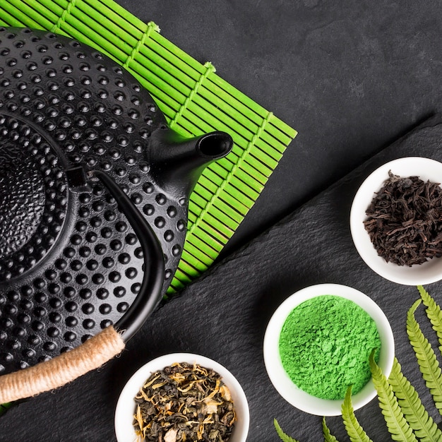 Close-up of healthy dry herb and matcha tea powder on slate stone background