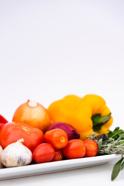 Крупный план здоровых свежих органических овощей в лотке на белом фоне