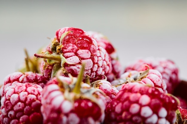 Close up heap of fresh raspberries on white wall.