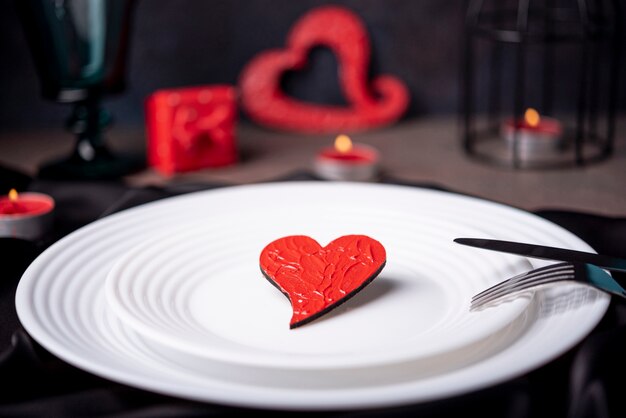 Close-up of heart on plates with cutlery and candles