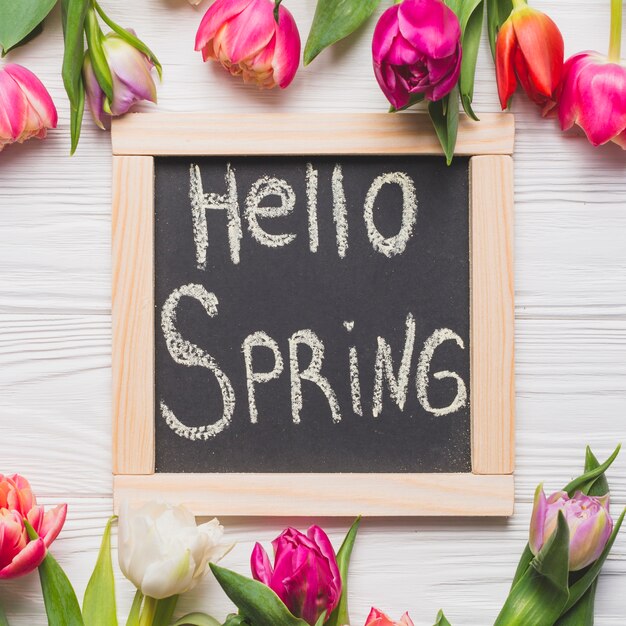 Крупный план Привет, весна, пишущая возле тюльпанов
