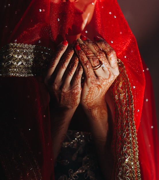 ヘナタトゥーで覆われているヒンズー教の花嫁の手のクローズアップ