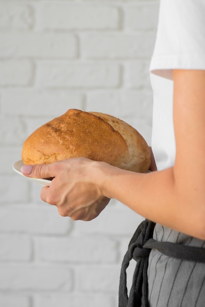 Foto gratuita primo piano che tiene pane rotondo fresco